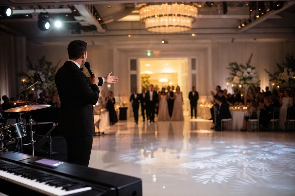 Wedding MC announcing reception introductions with entertainment team nearby